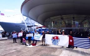 Demonstrators in Auckland hold up Morning Star flag to Indonesian sailors