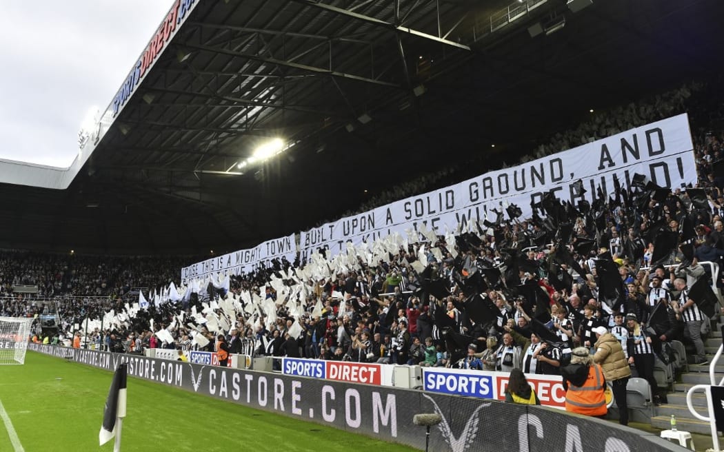 Newcastle United fans wave black and white flags and banners celebrating the club's recent take over by a Saudi-led consortium.