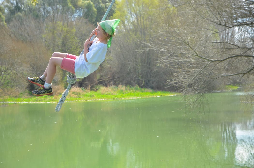Rosie Glover swings over the Selwyn River. She does not swim anymore because of the toxic green slime covering large stretches of it.