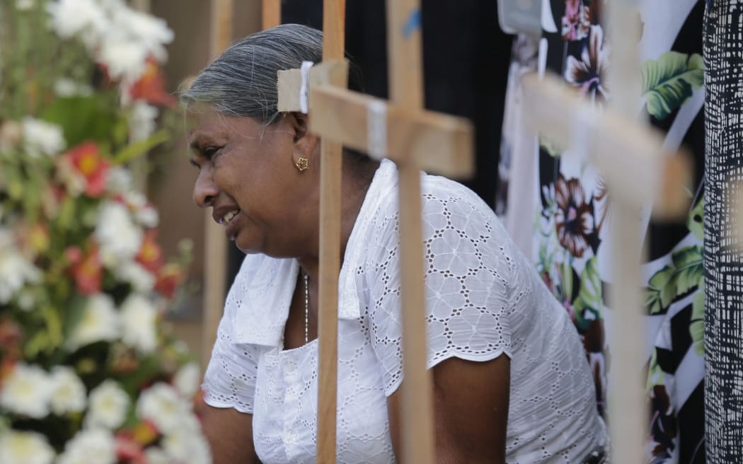 An elderly Sri Lankan woman cries sitting next to the grave of her family member who died in a Easter Sunday church explosion in Katuwapitiya village in Negombo, Sri Lanka