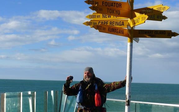 Bruce Hopkins poses underneath the Bluff signpost, the official end of Te Araroa.