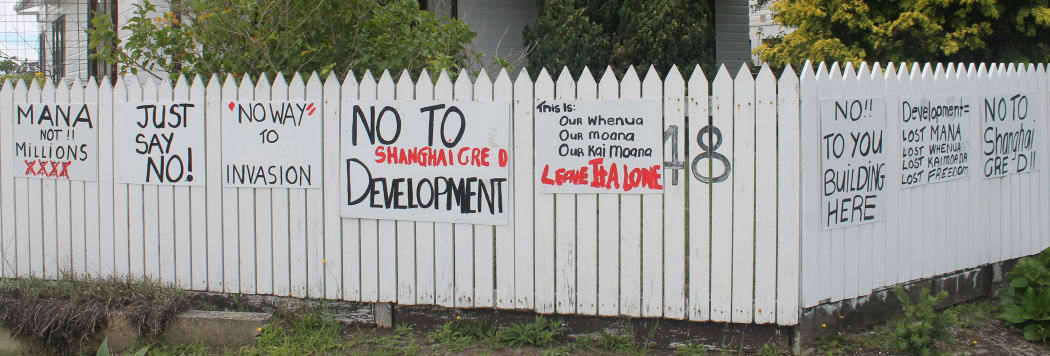 A fence in Whatuwhiwhi with sings on it expressing objection to foreign development.