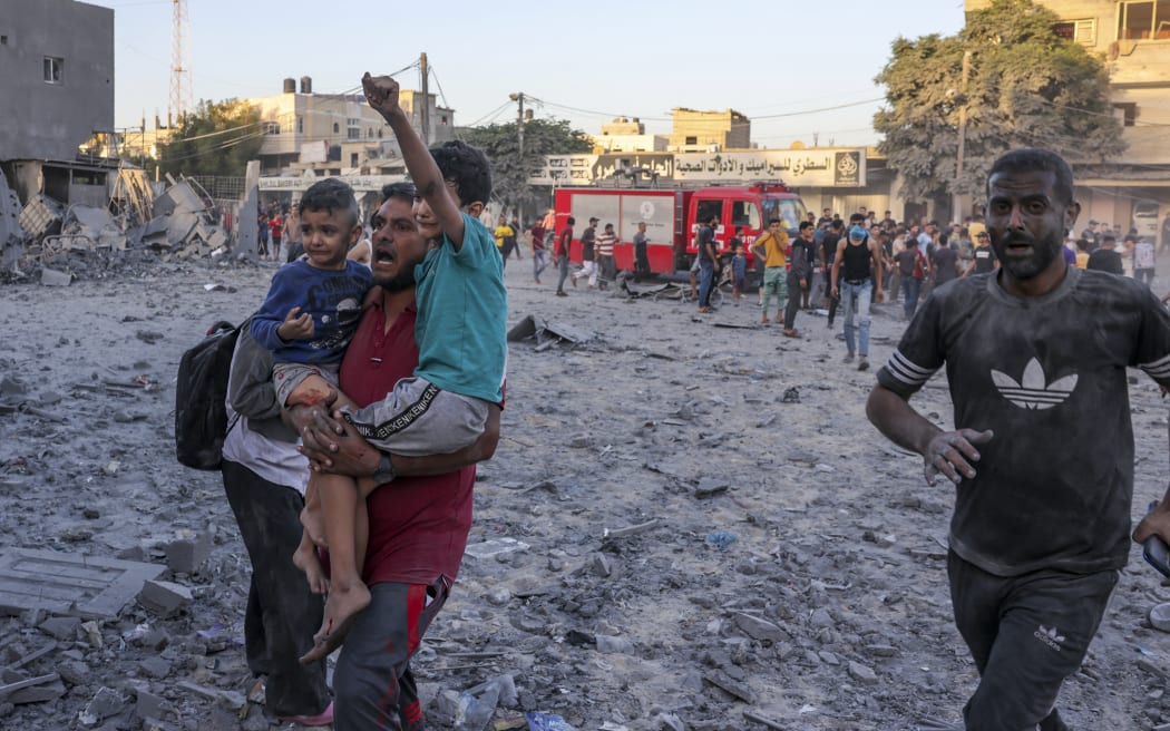 A wounded Palestinian man carries children following a strike in Rafah on the southern Gaza Strip on November 6, 2023, amid the ongoing battles between Isreal and the militant group Hamas. (Photo by Mohammed ABED / AFP)