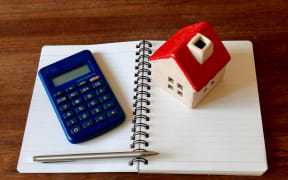 A calculator, a model of a house, a pen and a notebook - to illustrate financial planning and household budgets.