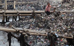 An Indonesian child collects rubbish on the coast near a fishing village in Jakarta, Indonesia.