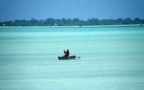 A man paddles his canoe in Kiribati