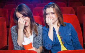 Women cry in a movie cinema.