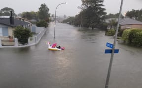 A man paddles an inflatable unicorn up the road, on Essex Street, Napier.