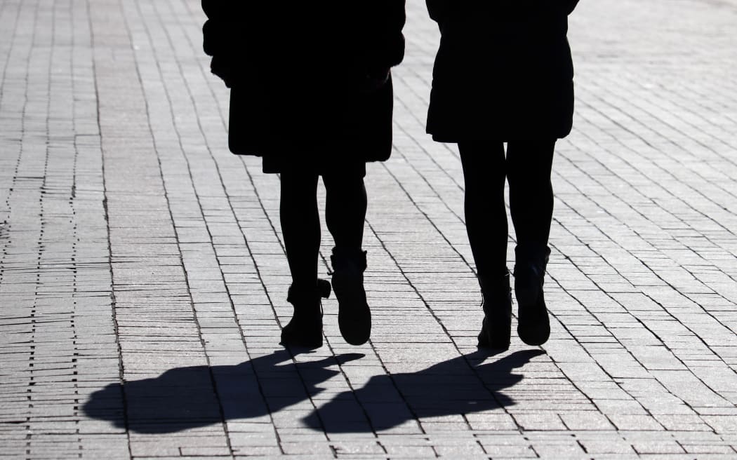 Silhouettes and shadows of two women walking down the street.