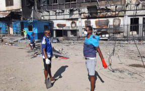 Members of the Fijian community in Honiara help BSP staff clean up. The bank was one of nearly 60 businesses torched by protesters last week.