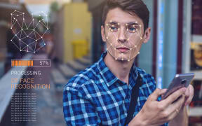 Biometric verification. Modern young man with the phone. The concept of a new technology of face recognition on polygonal grid is constructed by the points of IT security and protection
