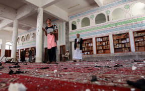 Armed men inspect the damage following a bomb explosion at the Badr mosque in southern Sanaa, Yemen.