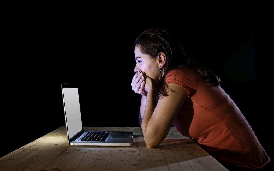 young and depressed worker or student woman working with computer laptop alone late at night in stress suffering internet bullying victim of social network
