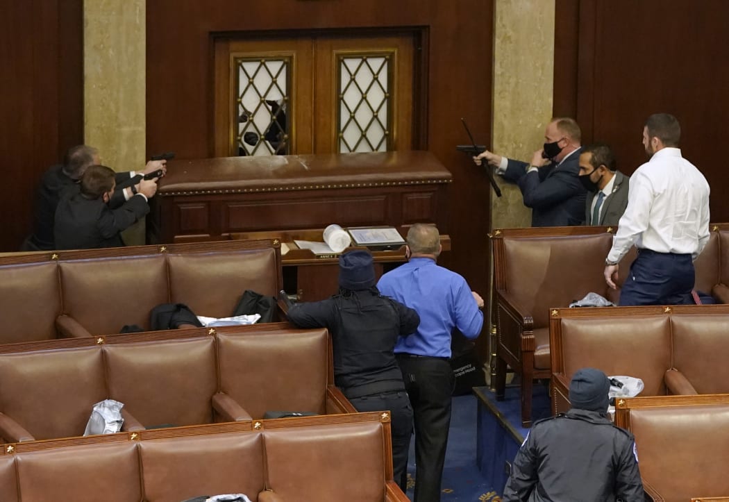 US Capitol police officers point their guns at a door that was vandalised in the House Chamber during a joint session of Congress on January 06, 2021 in Washington, DC.