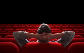 Image of happy male friends sitting in cinema watch film eating popcorn