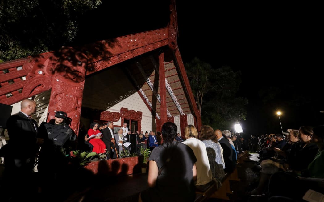 怀唐伊条约签署地，数百人在黑暗中聚集在 Te Whare Runanga 灯火通明的地方。