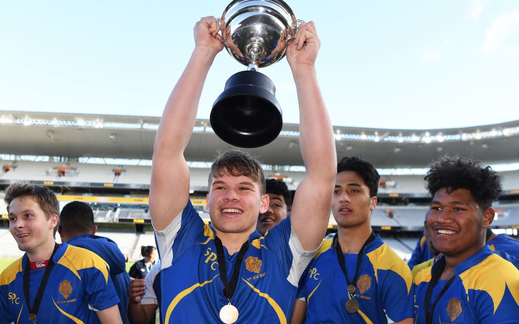 Niko Jones captain of the St Peters College First XV holds the Auckland second schools rugby trophy aloft.
