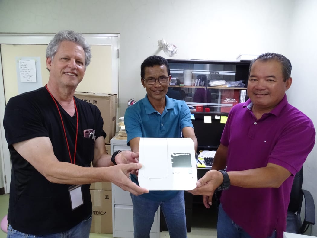 Marshall Islands Health Secretary Jack Niedenthal, left, joins Majuro hospital laboratory director Paul Lalita and Dr. Robert Maddison in showing Covid-19 test equipment