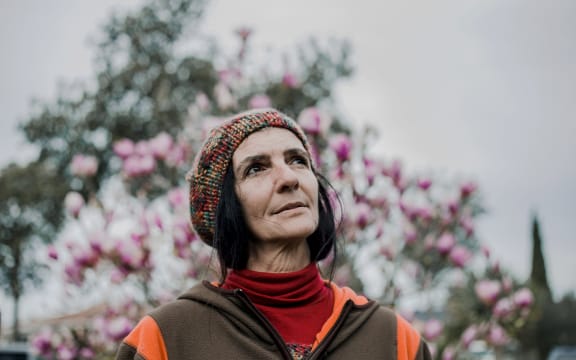Nadmea Carvalho stands in front of some flowers outside her home in Tāmaki