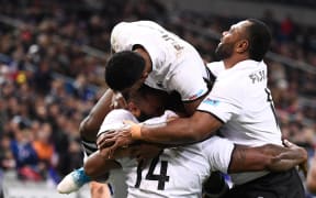 Fiji winger Josua Tuisova is mobbed by teammates after scoring a try.
