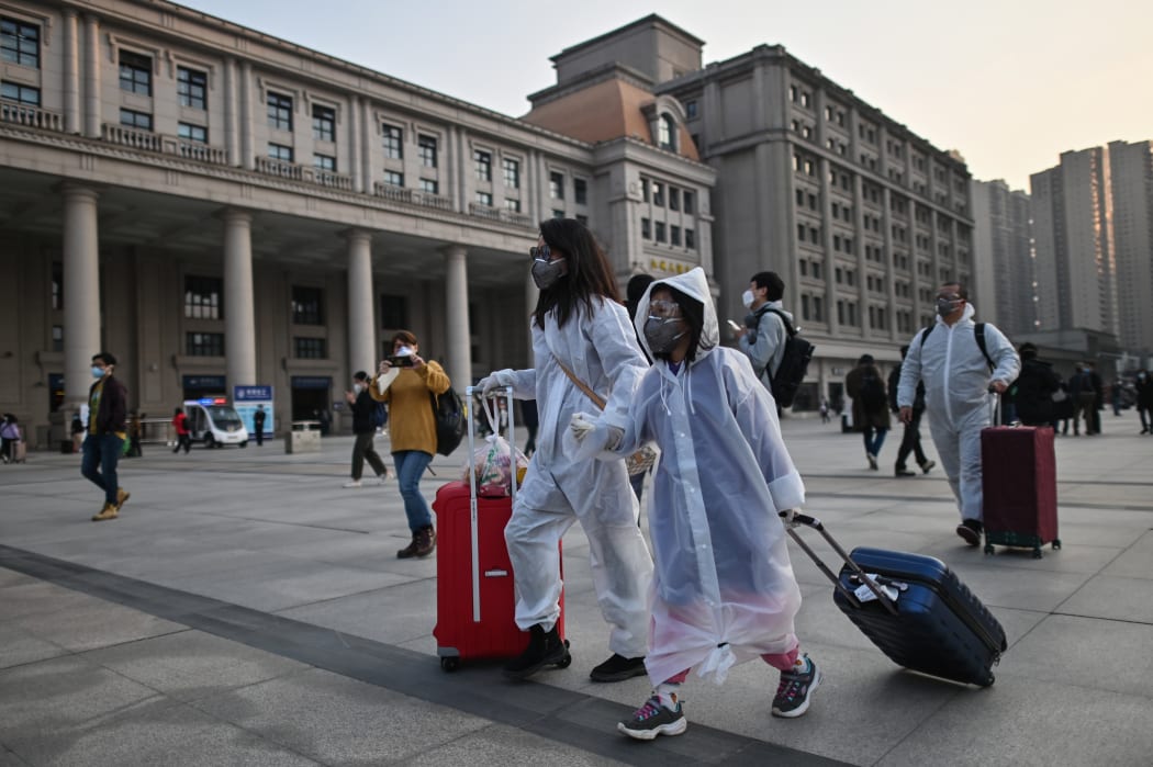 People wearing protective clothing and masks arrive at Hankou Railway Station to board one of the first trains to leave Wuhan after an outbound travel ban was lifted on April 8, 2020.