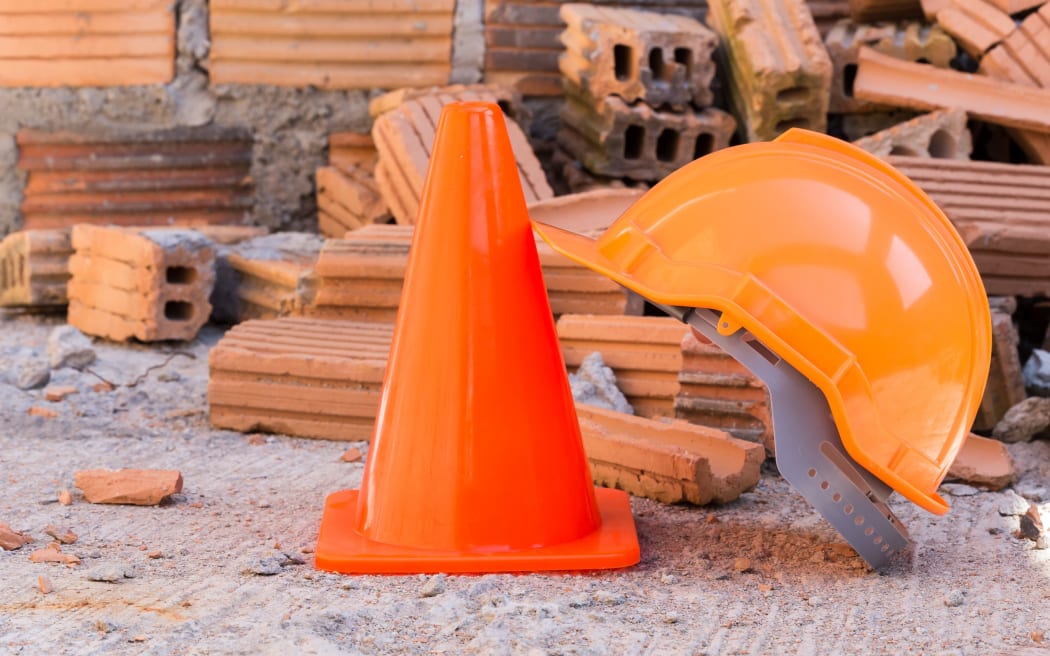 Helmet, cone and broken bricks at construction site.