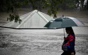 A woman walks past a flooded park along the overflowing Nepean river in Penrith on 21 March as Sydney braced for its worst flooding in decades.