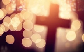 Abstract defocussed cross silhouette in church interior against stained glass window.