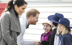 Prince Harry and Meghan talk to some schoolchildren outside Maranui Cafe.