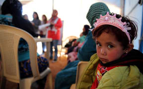 A child sits under a tent with Syrian refugee women attending a class on family planning organised by Doctors Without Borders (MSF) at a makeshift camp by Taybeh village, in Lebanon's eastern Bekaa Valley, on November 15, 2015.
