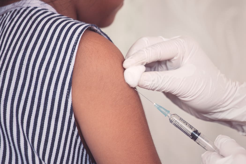Doctor injecting vaccination in arm of young girl.