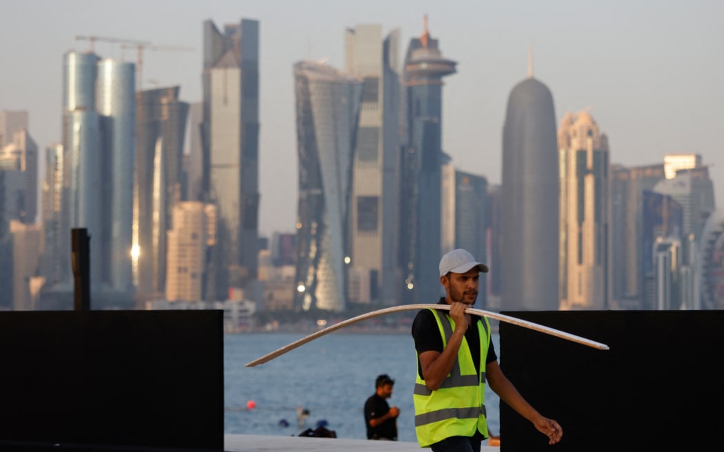 A worker carries wood at a construction site at the Corniche in Doha on 16 November, 2022, ahead of the Qatar 2022 FIFA World Cup football tournament.