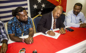 Mr Parkop signs the petition as Jeffrey Bomanak, Chairman of Free West Papua Movement (left) and James Yalya of NCD Governor’s Regional Office (right) look on.