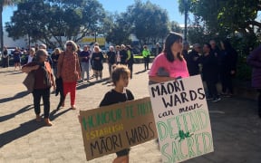 Supporters of Māori wards arrive at council carrying signs indicating what wards could mean for them. The sign “defend the sacred” carried by Lanae Cable refers to the potential development of the Opihi urupa at Whakatāne.