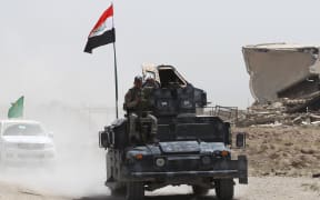 Iraqi government forces drive on a road near the village of al-Azraqiyah, northwest of the city of Fallujah, on June 5,
