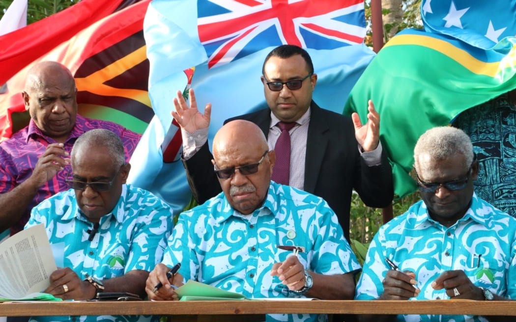 Sitiveni Rabuka, sitting middle, flanked by Vanuatu PM Ishmael Kalsakau, left, and Solomon Islands PM Manasseh Sogavare, right, signs up to the Udaune Declaration on Climate Change and the Efate Declaration on Security at the 22nd Melanesian Spearhead Group Leader's Summit in Port Vila. 24 August 2023