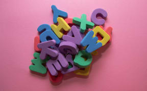Colorful plastic alphabet letters on pink background, top view.