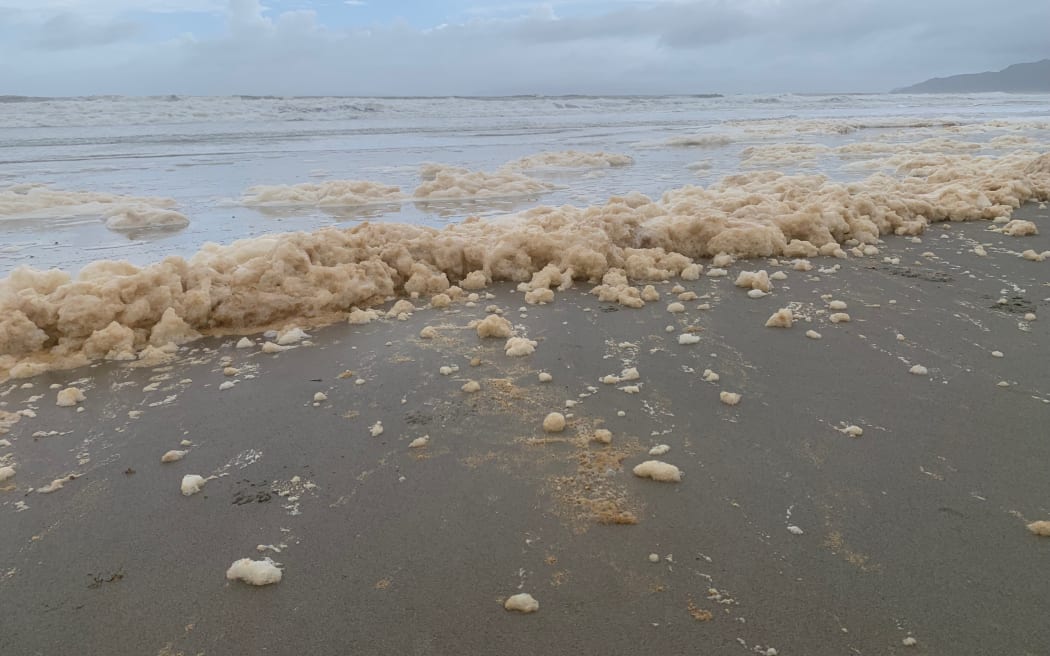 Froth covers the beach at Matarangi in the Coromandel, which has been cut off by land slips.
