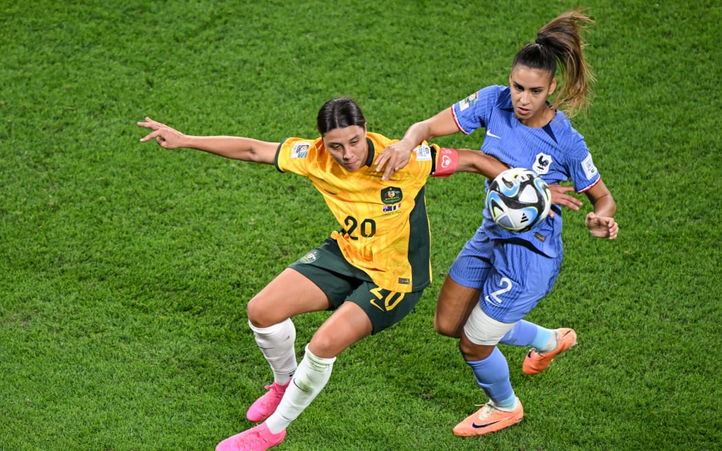 Australijski napastnik nr 20 Sam Kerr i francuska obrończyni nr 02 Myelle Lacrère walczą o piłkę podczas meczu ćwierćfinałowego Mistrzostw Świata Kobiet 2023 Australia – Nowa Zelandia pomiędzy Australią a Francją na stadionie Brisbane w Brisbane, 12 sierpnia 2023 r. William West /AFP)