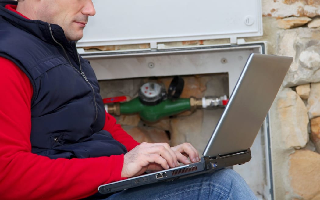 A man with a laptop takes water meter readings.