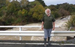 Mike Butler on a bridge above the raging Waiharakeke Stream