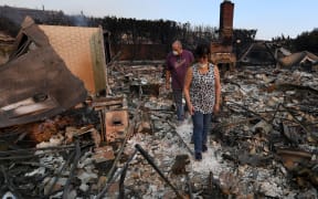 John and Julie Wilson sort through the remnants of their burnt out home after the Thomas wildfire swept through Ventura, California.