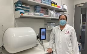 Dr. Rachel Perret beside the new cocoon equipment that will make CAR T-cells more efficiently.