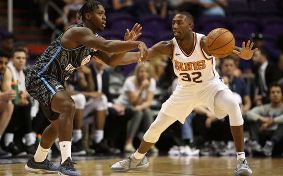Armani Moore of the New Zealand Breakers passes the ball around Davon Reed of the Phoenix Suns during the first half of their game.