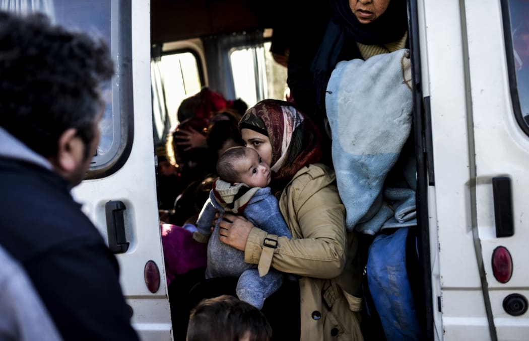 A woman holds an infant in a van after being detained by Turkish soldiers with other Syrians trying to reach the Greek island of Lesbos from Dikili, western Turkey, on March 5, 2016.