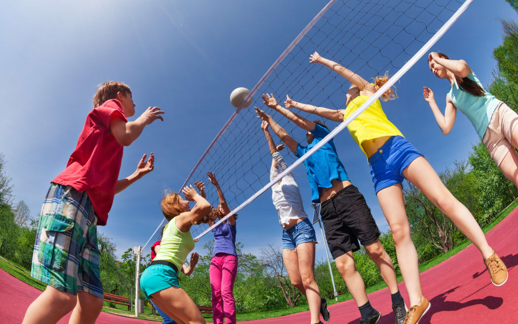 Adolescents jouant au volley-ball ensemble à l'extérieur par une journée ensoleillée.