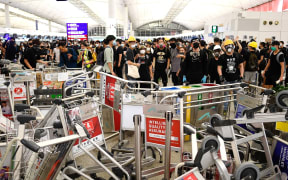 Pro-democracy protestors block the entrance to the airport terminals after a scuffle with police at Hong Kong's international airport on August 13, 2019
