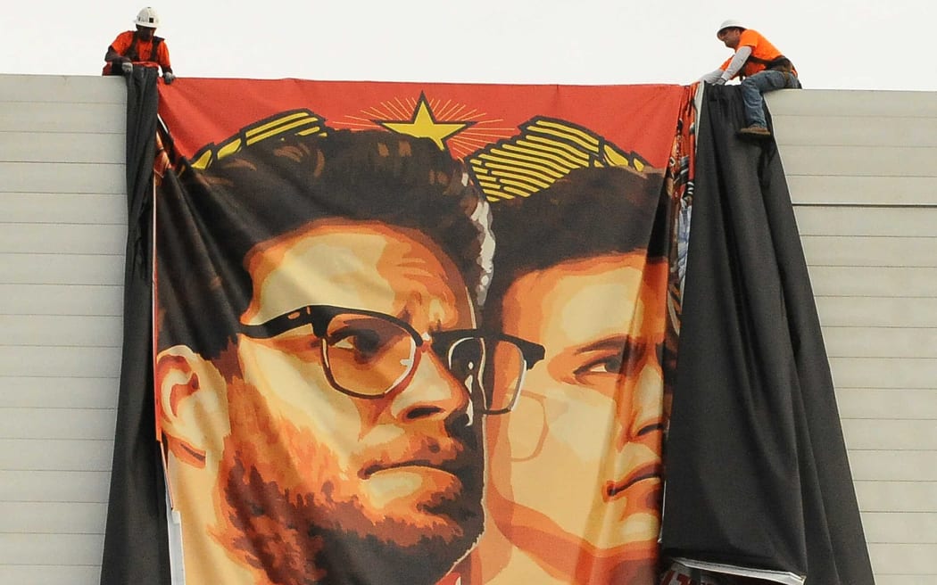 Workers remove a poster-banner for "The Interview" from a billboard in Hollywood.