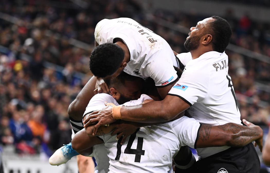 Fiji winger Josua Tuisova is mobbed by teammates after scoring a try.