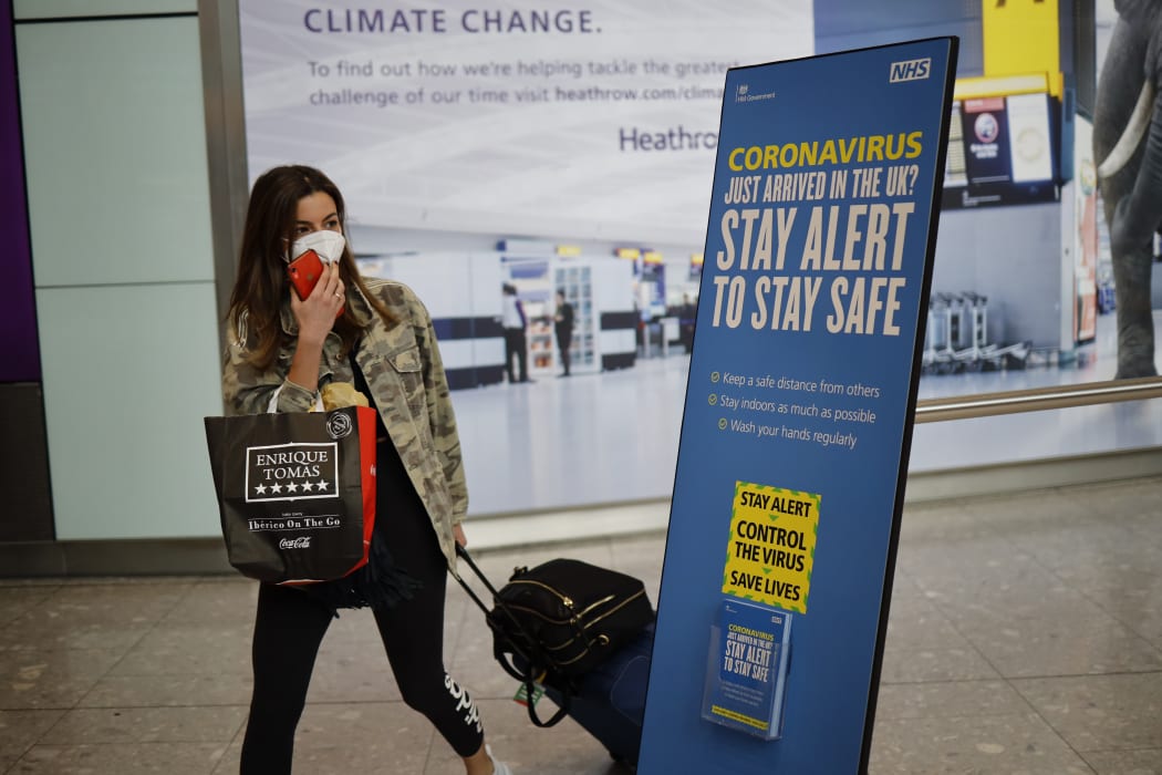 A passenger wearing a face mask as a precaution against the novel coronavirus walks past a sign at Heathrow airport, west London, on May 22, 2020.